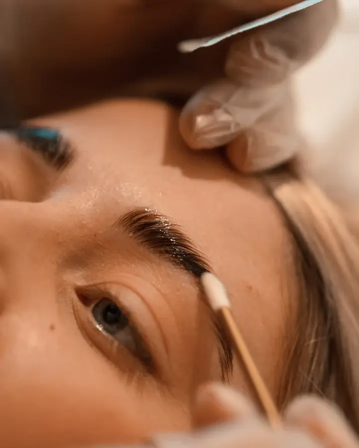 Designer de sobrancelha aplicando henna com pincel em uma cliente