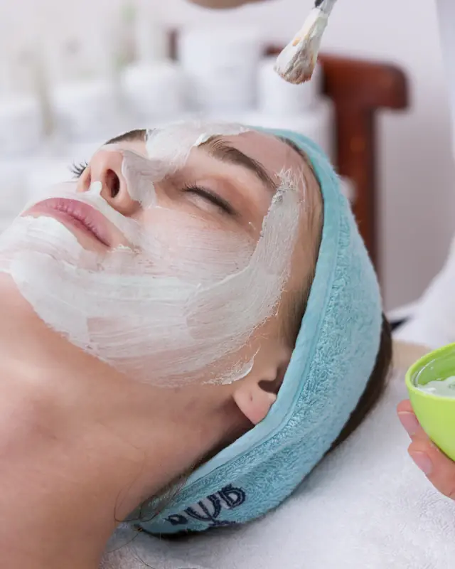 Esteticista aplicando máscara facial com pincel em uma cliente